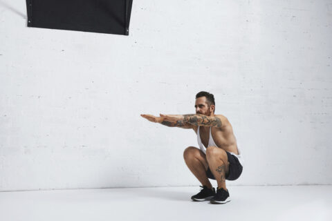 Homem faz um agachamento profundo como parte de seus exercícios de mobilidade.