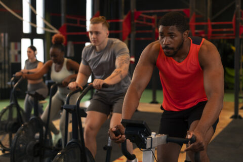 Grupo de pessoas realizando treino híbrido na academia, combinando exercícios aeróbicos e de resistência para melhorar o condicionamento físico.