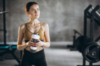 Mulher na academia segurando uma coqueteleira de suplementos