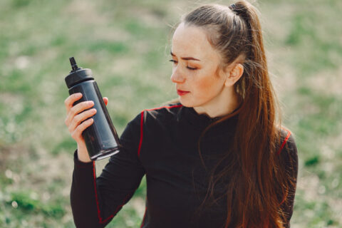 Mulher com roupa esportiva segura uma garrafa como se perguntasse se pode tomar whey sem treinar