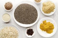 Chia, cúrcuma, aveia, linhaça e outros alimentos funcionais dispostos em uma mesa.